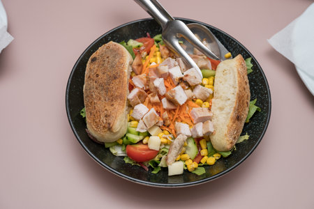 A plate of chicken salad, fresh vegetables including lettuce, tomatoes, cucumbers and corn, small pieces of cheeseの写真素材
