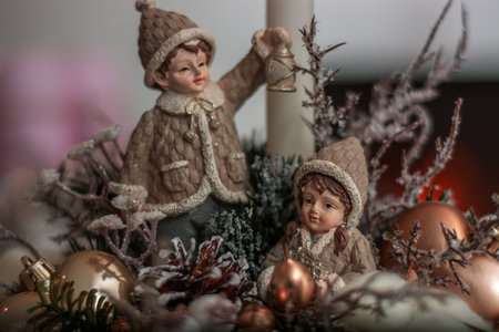 a close-up of Christmas-themed decorative figurines and ornaments. The central figures are two small, intricately detailed figurines of children dressed in winter clothing,の写真素材