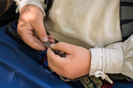 a person repairing a metal chain part of a traditional costume or historical reenactment gear....