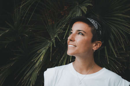 Portrait of a beautiful dreamy woman with a beautiful smile and short hair looking up smiling with...