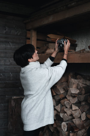 Photographer setting up her film camera over a wooden shelf during winterの写真素材