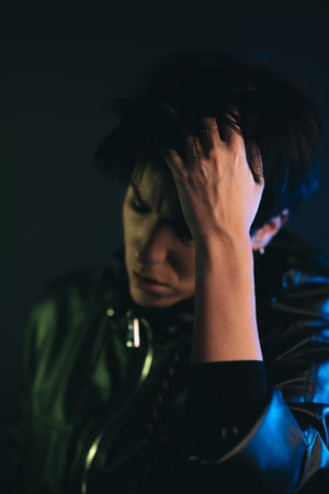 Portrait of a stylish woman with short hair and leather jacket in studio touching her hairの写真素材