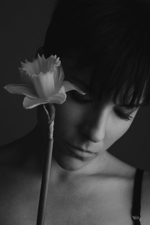 Black and white portrait of a woman with her eyes closed holding a daffodil in studioの写真素材