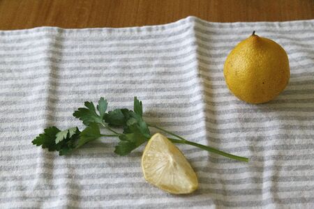 Front shot of lemons and parsley over a kitchen towel on a wooden tableの写真素材