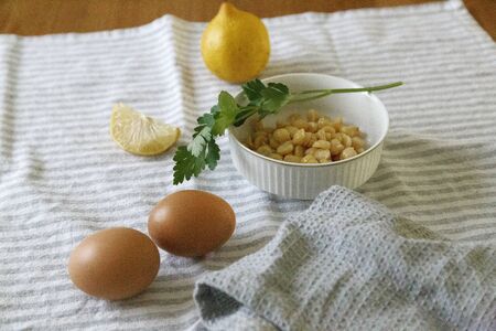 Front Shot of eggs, parsley, chickpeas, and lemons over a kitchen towel on a wooden tableの写真素材