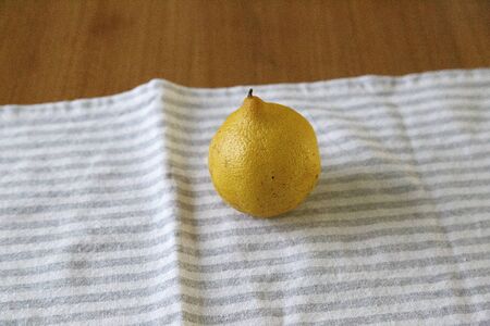 Front shot of a lemon over a kitchen towel on a wooden table. Copy Spaceの写真素材