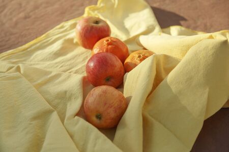 Front Shot of organic apples and tangerines over a yellow tablecloth on a red floorの写真素材
