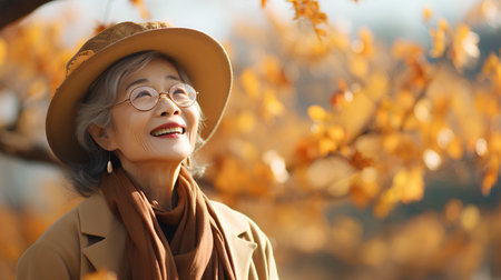 Portrait of smiling senior woman in hat and coat in autumn parkの素材