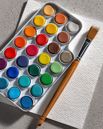 Watercolor paints and brush on a white table. Top view.の素材
