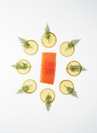 Slices of fresh salmon with dill and lemon on white backgroundの素材