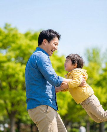 Asian father and son playing together in the park with blue sky backgroundの素材