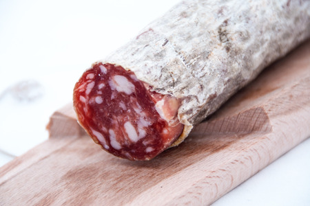 close up of a cutting board with italian salame on white background