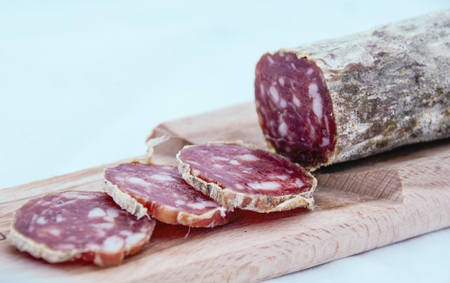 close up of a cutting board with italian salame on white background