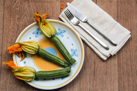 plate of courgettes with their flower on a wood tableの写真素材