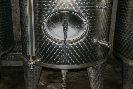 AT TUFO - ITALY - ON 11/ 19/2016 - detail of a wine barrel tap on a modern tank in a cellarのeditorial素材