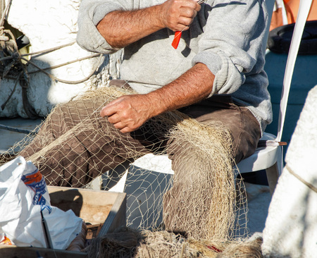 fisherman repairing a fishnet in his boat , pozzuoli port, Naples, Italy