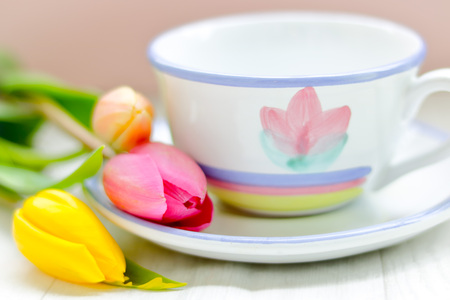 springtime background with a nicely decorated cup of tea and fresh tulips on a wooden backgroundの写真素材
