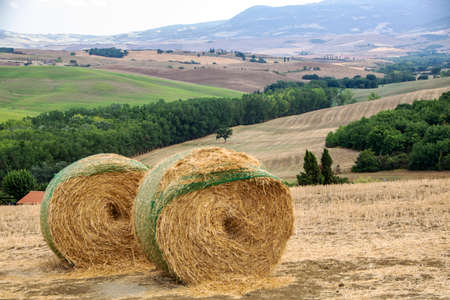 Landscape of Tuscan countryside with stacks of wheat straw in a fieldの写真素材