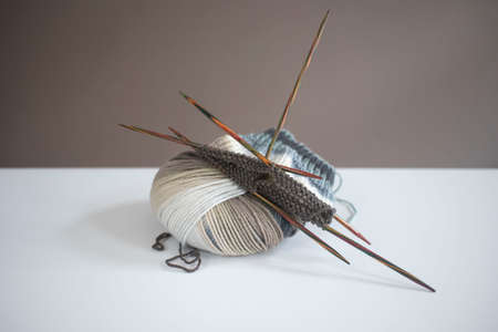 Ball of yarn and double pointed needles on white table in daylight. Close-up, bright. Knitting socks.の写真素材