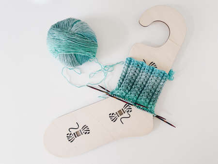 Knitting socks on wooden sock holder. Ball of yarn and needles flatlay.の写真素材