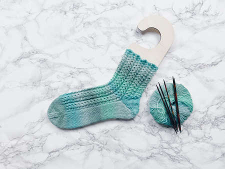 Knitting socks on wooden sock holder. Yarn and needles flatlay.の写真素材