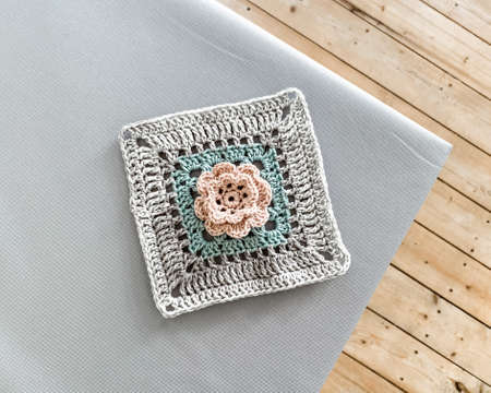 Crochet granny square with flower. Flatlay with wooden floor.の写真素材