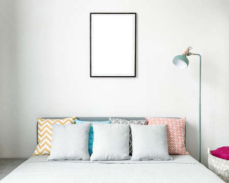 Double bed with colored pillows and empty picture frame.