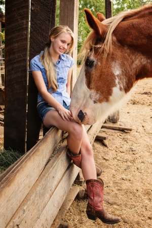 Young Girl sitting on a wood fence with Clydesdaleの写真素材