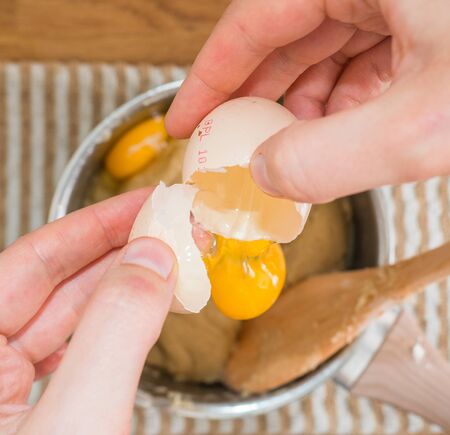 Breaking an egg on top of baking mix. Egg falling into the cake mix from above.