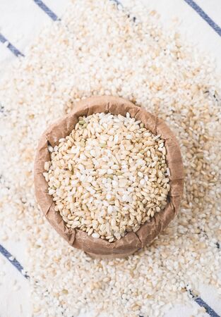 Rice grain in a paper bag over white kitchen table. View form above.の写真素材