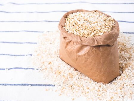 Rice grain in a paper bag over white kitchen cloth. View form above.の写真素材