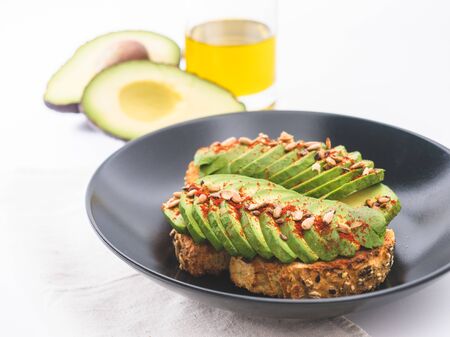 sourdough toast with avocado and spanish paprika powder. Fresh avocado and olive oil in the backgroundの写真素材