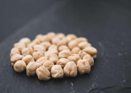 Dry chickpeas on an isolated black board. Slate tray. Black Background. Angle view. Depth of field.の写真素材