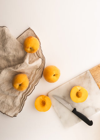 Peaches seen from above. Chopping board with a knife and a cloth on the side.