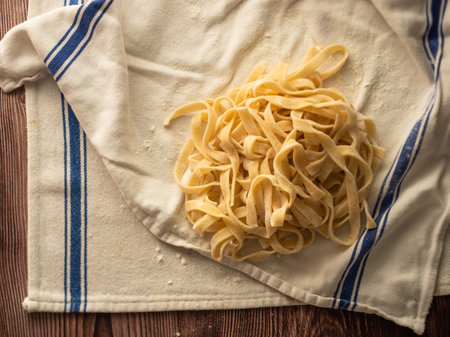 Fresh pasta and kitchen cloth on a wooden tableの写真素材