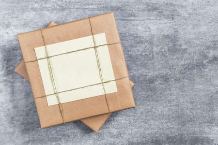 Gift box wrapped in kraft paper and tied with jute thread on a gray background. A universal template...