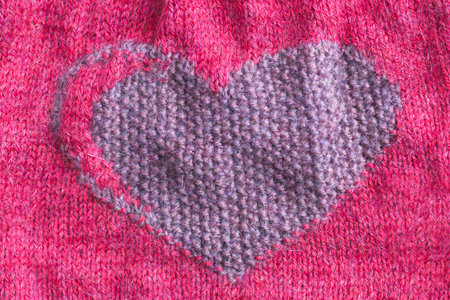 Knitted fabric with a heart close-up. Valentines Day. Hobby, handicraft.