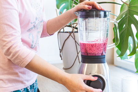 A woman mixes berry smoothie in a blender. The concept of a healthy lifestyle.の写真素材