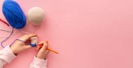 Childrens hands in the process of crocheting toys from blue and beige yarn.の写真素材