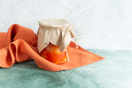 Canned vegetables in a glass jar and a terracotta linen napkin on a light green background. Homemade...