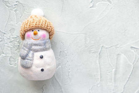 Ceramic Christmas toy - a cute snowman in a knitted hat with a pompom and a scarf on a light green background. New year and christmas concept. Card. Copy space.の写真素材
