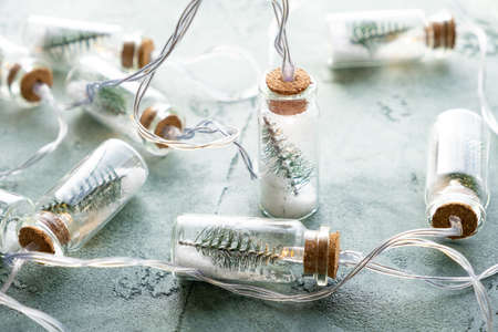 Concept of new year and christmas, cozy winter evening. Beautiful glass electric garland close-up with Christmas trees and snow inside on a textured green background. Preparing for the winter holidaysの写真素材