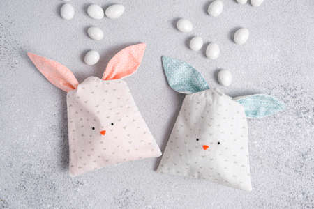 Two bag of sweets in shape of Easter bunny with blue and pink ears on light gray background. Packing...