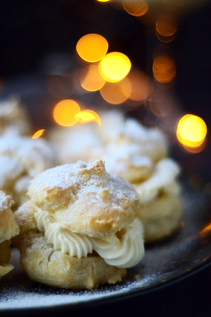 Profiteroles with powdered sugar on a dark background