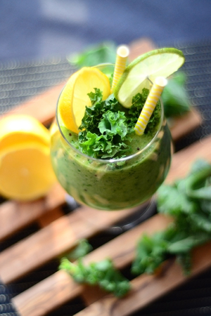 Green organic smoothie with fresh kale, kiwi and lime on wooden padの写真素材