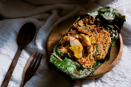 Nasi Goreng or Fried Rice Traditional Food Wrapped in Leaf on Wooden Plateの写真素材