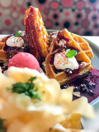 Sweet food waffles with strawberry, and blueberry sauce, ice cream, candy and chips with close up angleの写真素材
