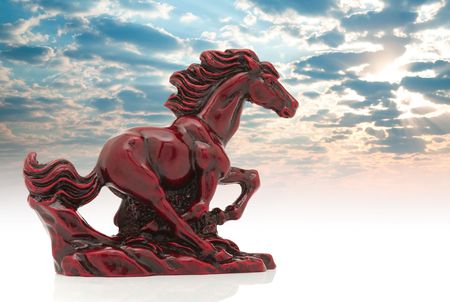Old-fashioned figurine red horse  on cloudscape background.の写真素材
