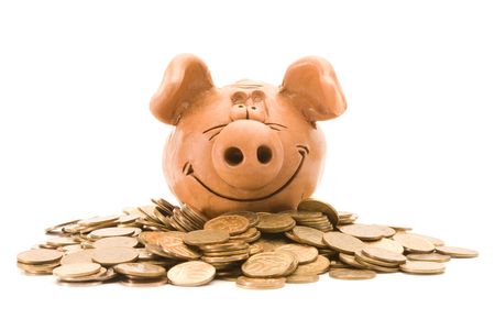 Pig bank seat on a heap of coins isolated over white backgroundの写真素材