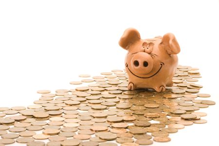 Pig bank seat on a heap of coins isolated over white backgroundの写真素材